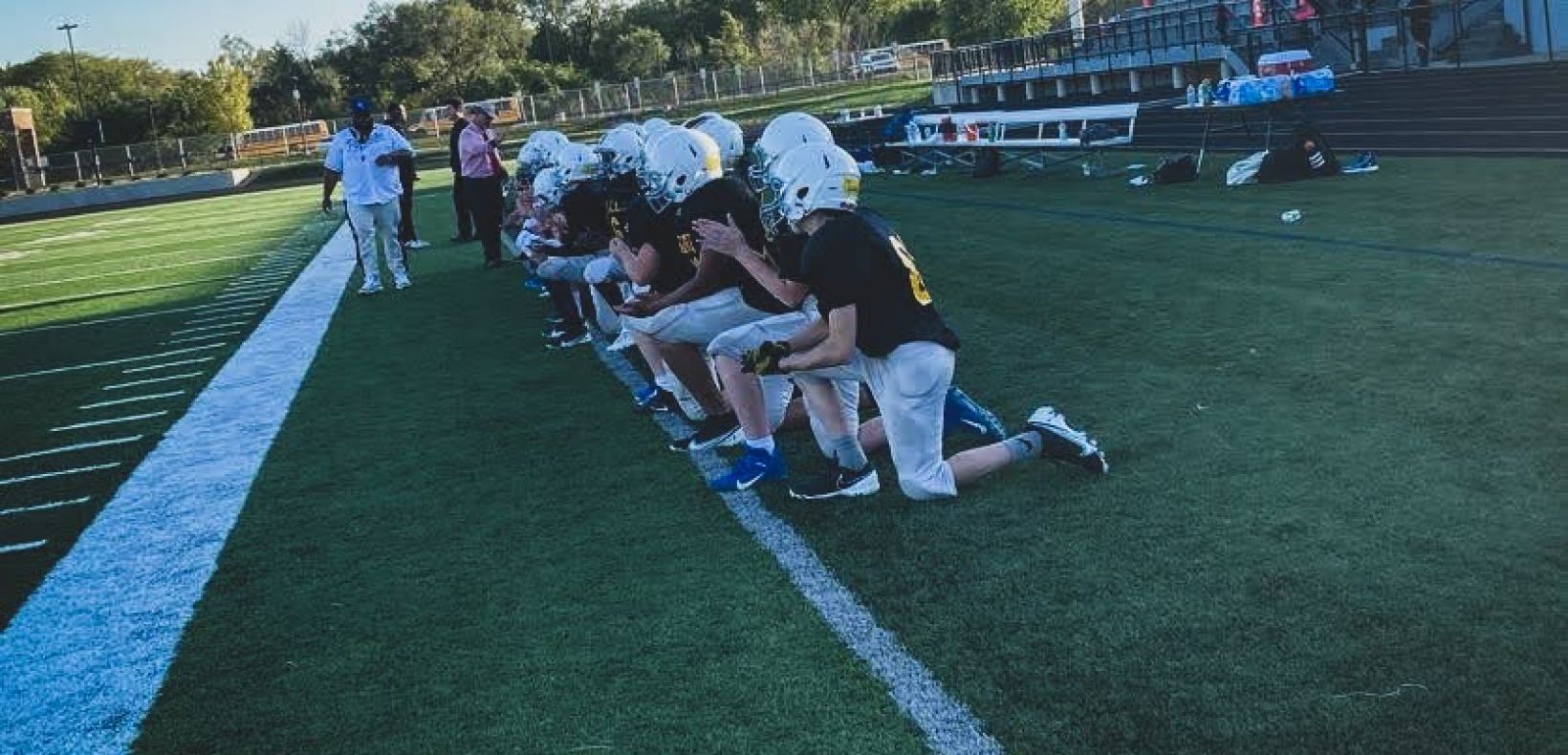 team of football players kneeling looking onto the field